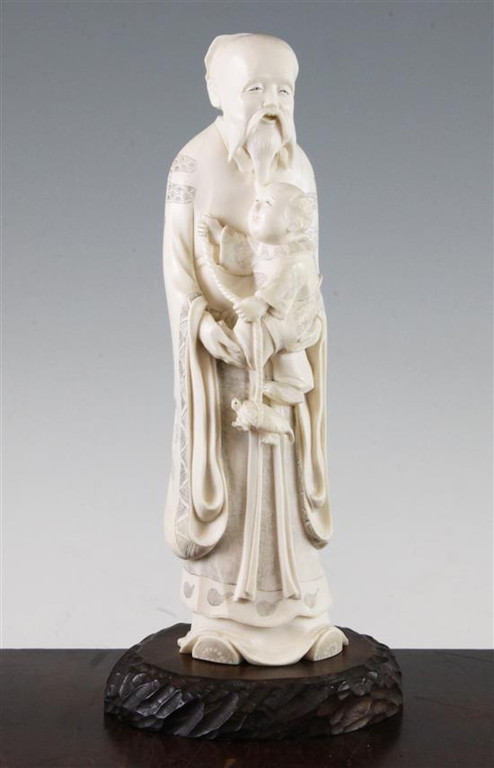 A large Japanese ivory figure of an old man holding a boy, early 20th century, 25.5cm, wood stand